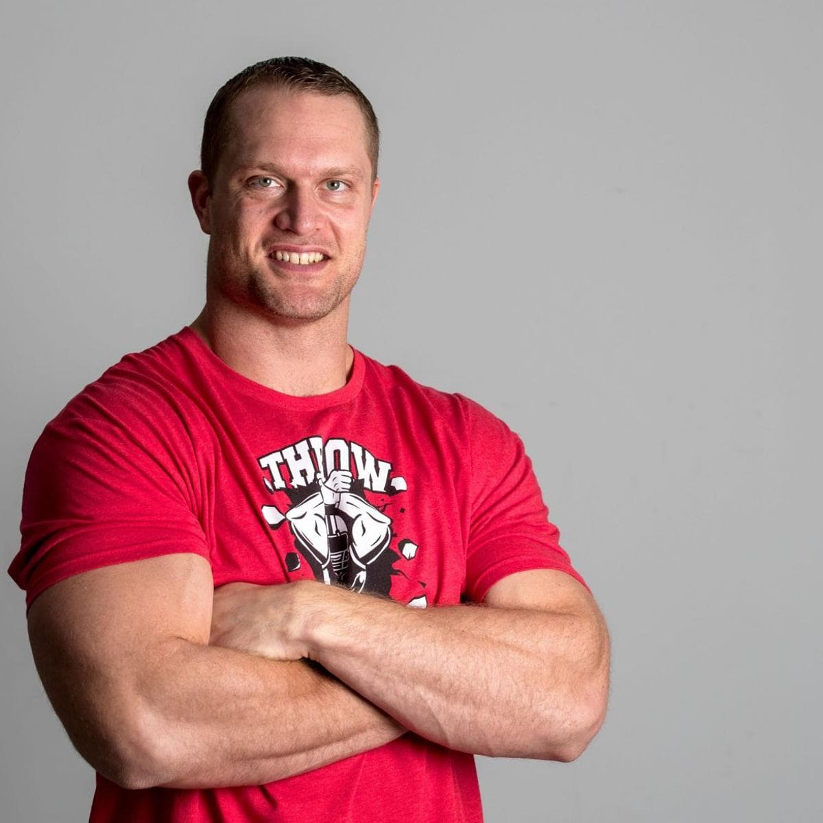 Adam Carriker, arms folded, in a red Carriker Chronicles shirt